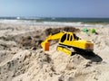 Plastic excavator child toy digging holes on the beach