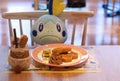 Plastic food on a table in the PokÃÂ©mon CafÃÂ© with a plush toy sitting behind it.