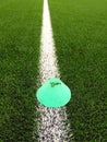 Plastic football green turf playground with grinded black rubber in core and bright green blue plastic cone. White line marks