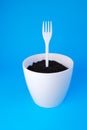 Plastic fork in a white flower pot on a blue background. Ecology. Ecological problem Royalty Free Stock Photo