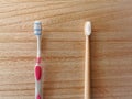 Plastic free lifestyle swap concept with a plastic toothbrush and a bamboo toothbrush as sustainable alternative on a wooden