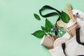 Plastic free set with cotton bag, glass jar, green leaves and recycled tableware top view. Zero waste, eco friendly concept.