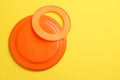 Plastic frisbee disk and ring on yellow background, flat lay. Space for text
