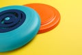 Plastic frisbee disks on yellow background, closeup