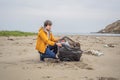 Plastic garbage. Sea and ocean pollution. Beach clean up. Young man picking used plastic bottles on sand shore Royalty Free Stock Photo