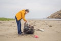 Plastic garbage. Sea and ocean pollution. Beach clean up. Young man picking used plastic bottles on sand shore Royalty Free Stock Photo