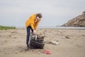 Plastic garbage. Sea and ocean pollution. Beach clean up. Young man picking used plastic bottles on sand shore Royalty Free Stock Photo