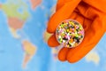Plastic granules in hands with orange gloves on the background of the world map .The concept of Plastic pollution. Selective focus Royalty Free Stock Photo