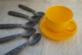 plastic gray toy spoons and a yellow cup Royalty Free Stock Photo