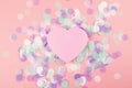 Plastic heart on pink background with confetti