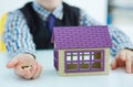 Plastic house toy and money in little boy`s hands. Invest in real estate.