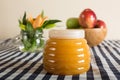 Plastic jar of honey, a pot of beautiful orange lilium flowers with green leaves and bulbs and a bowl of red and green apples Royalty Free Stock Photo