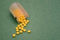 Plastic jar with yellow pills. Round yellow pills are scattered on a green background. Top view, copy space Royalty Free Stock Photo