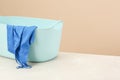 Plastic laundry basket with clothes near beige wall. Space for text Royalty Free Stock Photo