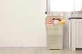 Plastic laundry basket full of dirty clothes on floor near light wall in room