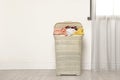 Plastic laundry basket full of dirty clothes on floor in room. Space for text Royalty Free Stock Photo