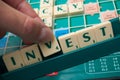 Plastic letters on Scrabble board game forming the word : Invest Royalty Free Stock Photo