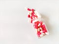 A clear plastic jar, partially opened, spills pink and white capsules onto a white surface. p Royalty Free Stock Photo