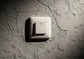 A plastic light switch is mounted on a textured gray wall. The wall Royalty Free Stock Photo