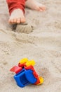 Little car, children toys and feet of little boy. Relax or playing on sand at beach. Summer and vacation time Royalty Free Stock Photo