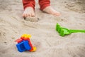 Little car, children toys and feet of little boy. Relax or playing on sand at beach. Summer and vacation time Royalty Free Stock Photo