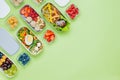 Plastic lunch boxes filled with healthy food on green background