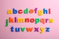 Plastic magnetic letters on pink background. Alphabetical order Royalty Free Stock Photo