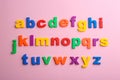 Plastic magnetic letters on pink background. Alphabetical order