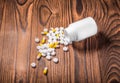 A plastic medicine bottle with a lot of pills, vitamins, and capsules on a wooden table. Health care tablets. Royalty Free Stock Photo