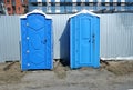 plastic mobile dry closets on a construction site for workers against the background of a metal temporary fence.