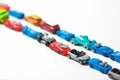 Plastic multi-colored toy cars are lined up on a white background. Stereotypical alignment of subjects is a sign of autism.