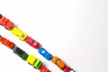 Plastic multi-colored toy cars are lined up on a white background. Stereotypical alignment of subjects is a sign of autism.