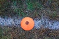 Plastic orange disk with a hole in the center on a white line painted on grass