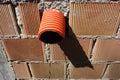 Plastic escape drain pipe in a hole of a red brick house wall Royalty Free Stock Photo