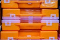 Plastic orange tool boxes on store shelves. Stack of organizers close-up