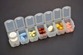 Plastic daily organizer for pills, box with different pills on black background with a copyspace, top view Royalty Free Stock Photo