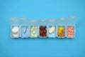 Plastic daily organizer for pills, box with different pills on blue background with copyspace, top view Royalty Free Stock Photo