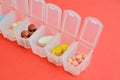 Plastic daily organizer for pills, box with different pills on pink background with copyspace Royalty Free Stock Photo