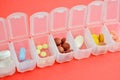 Plastic daily organizer for pills, box with different pills on pink background with copyspace, top view Royalty Free Stock Photo