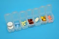 Plastic daily organizer for pills with different pills on blue background with copyspace, top view Royalty Free Stock Photo