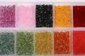 Plastic organizers with different beads as background, top view