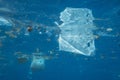 Plastic and other debris floats underwater in blue water. Plastic garbage polluting seas and ocean Royalty Free Stock Photo