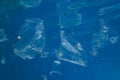 Plastic and other debris floats underwater in blue water. Plastic garbage polluting seas and ocean Royalty Free Stock Photo