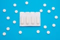 Plastic packaging with vaginal or rectal suppositories is on blue background surrounded by round tablets that form ornament in pol Royalty Free Stock Photo