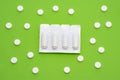 Plastic packaging with vaginal or rectal suppositories is on green background surrounded by round tablets that form ornament in po