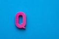 Alphabet letter Q - Pink plastic piece on blue foamy background
