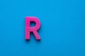 Plastic pink letter R uppercase on blue foamy background