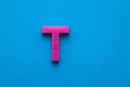Plastic pink letter T uppercase on blue foamy background