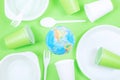 Plastic, pollution, Ecology, recycling concept. Plastic disposable tableware and earth globe on green background