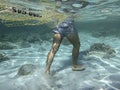 Plastic pollution in the ocean and in the sea: underwater shot of a man walking on the seabed dragging a fishing net and a piece